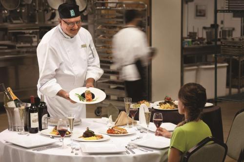 a chef holding a plate of food on a table at Embassy Suites by Hilton Orlando Lake Buena Vista South in Kissimmee
