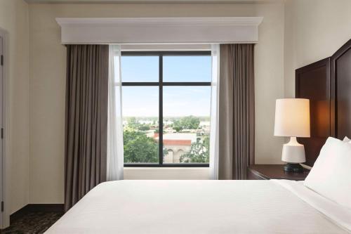 a bedroom with a bed and a large window at Embassy Suites by Hilton Orlando Lake Buena Vista South in Kissimmee