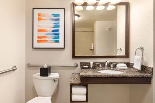 a bathroom with a toilet and a sink with a mirror at Embassy Suites by Hilton Orlando Lake Buena Vista South in Kissimmee
