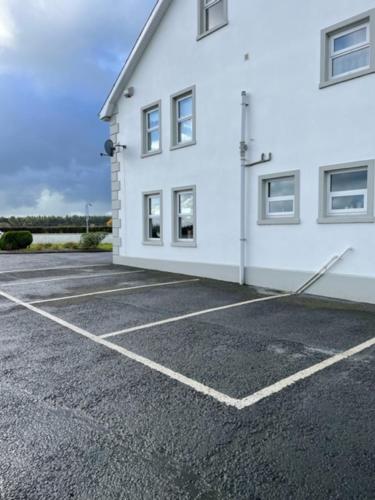 ein weißes Gebäude mit einem Parkplatz daneben in der Unterkunft New Lisnagalt Lodge in Coleraine