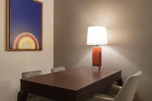a table with a lamp and chairs in a room at Embassy Suites by Hilton Orlando Lake Buena Vista South in Kissimmee
