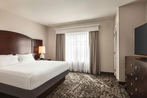 a hotel room with a bed and a large window at Embassy Suites by Hilton Orlando Lake Buena Vista South in Kissimmee