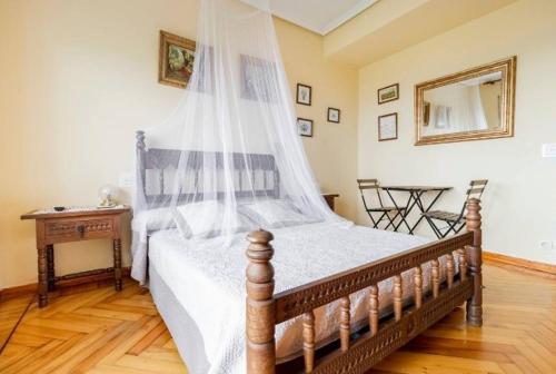 a bedroom with a bed with a canopy and a table at CASA FINCA LA GARITA in Santillana del Mar