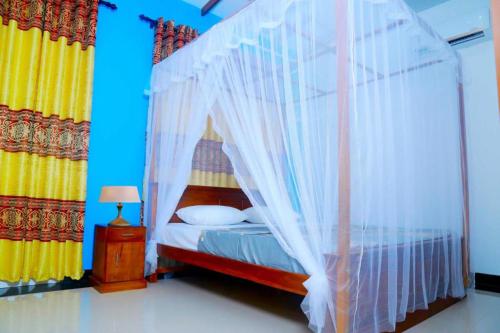 a bedroom with a canopy bed with white curtains at villa surendra in Weligama