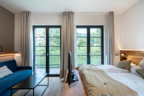 ein Schlafzimmer mit einem Bett, einem Sofa und Fenstern in der Unterkunft Resort Aurum Residence A in Černý Důl