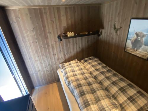 a small bed in a room with a plaid blanket at Moderne hytte i Svandalen, Sauda - nær skisenter og natur in Sauda