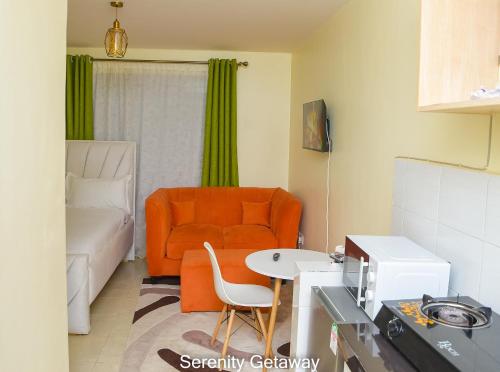 een woonkamer met een oranje bank en een tafel bij Serenity Getaway STUDIO apartment near JKIA & SGR with KING BED, WIFI, NETFLIX and SECURE PARKING in Syokimau