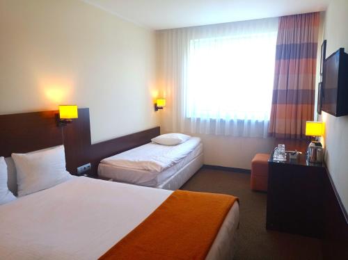 a hotel room with two beds and a window at Desilva Inn Katowice Airport in Pyrzowice