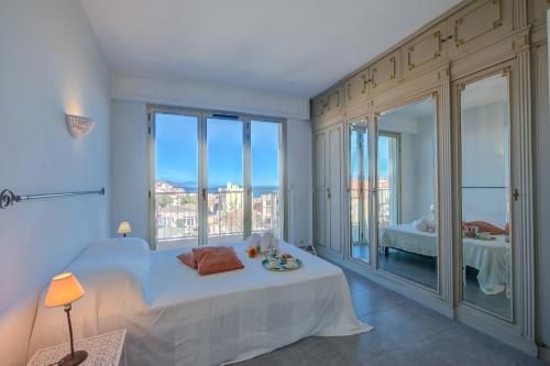 une chambre blanche avec un lit et un balcon dans l'établissement Appartement Le Fabiola - Happy Rentals, à Antibes