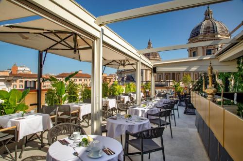 ローマにあるThe Major Hotelの白いテーブルと椅子のあるパティオ付きのレストラン