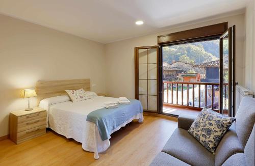 a bedroom with a bed and a couch and a balcony at Casa Celis 2 in Espinaredo