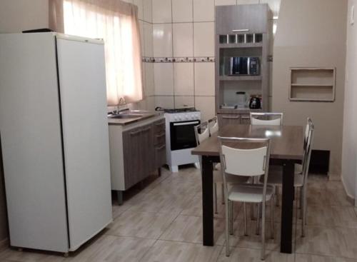 eine Küche mit einem Tisch mit Stühlen und einem Kühlschrank in der Unterkunft Cabana 2 qts com Ar-condicionado in Machadinho