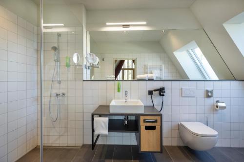 a bathroom with a sink and a toilet and a mirror at JUFA Hotel Bregenz in Bregenz