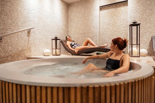 Dos mujeres sentadas en una bañera en un baño en Hotel Spa Republica en Mar del Plata