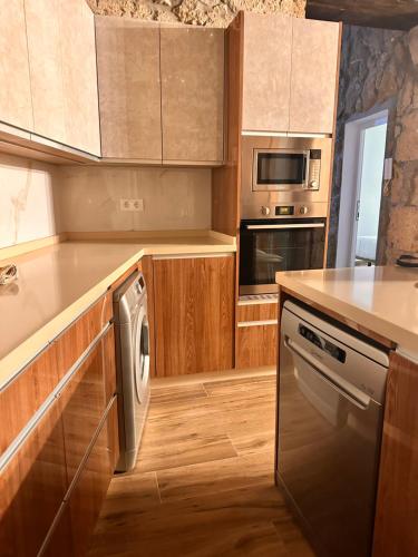 cocina con armarios de madera y lavavajillas en CASA EL ROQUE, en Telde