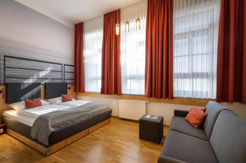 a bedroom with a bed and a couch at JUFA Hotel Bregenz in Bregenz