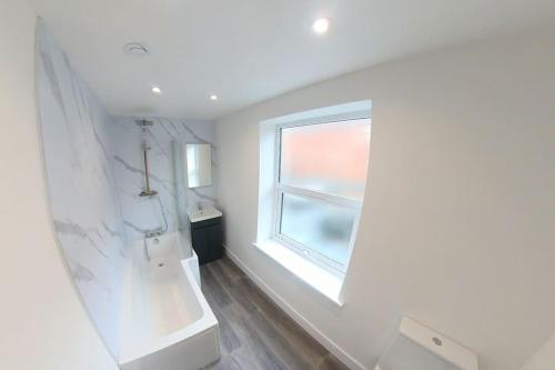 a white bathroom with a window and a sink at Imperial Apartments. Brand New, 2 Bed In Goole. in Goole