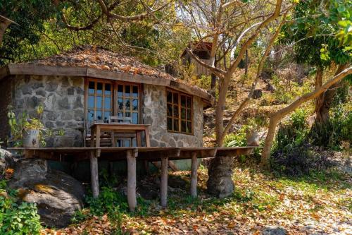 une petite maison en pierre avec une table et un banc dans l'établissement Butterfly Space- A Non-Profit Eco-Lodge, à Nkhata Bay