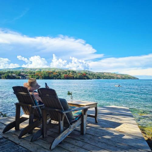 a woman sitting in a chair at a table on a dock at Butterfly Space- A Non-Profit Eco-Lodge in Nkhata Bay