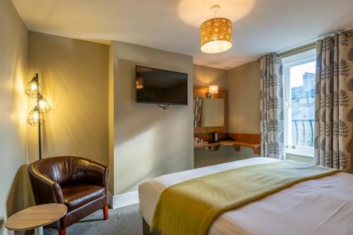 a bedroom with a bed and a chair and a tv at Castle Court in Beaumaris