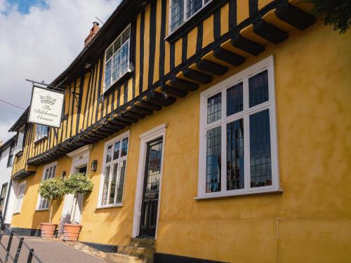 un edificio amarillo con ventanas blancas en una calle en The Bildeston Crown, en Bildeston