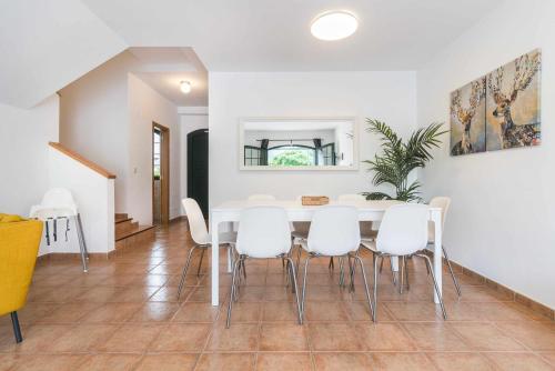 a dining room with a white table and white chairs at Residencial Las Candelarias 34 in Agaete
