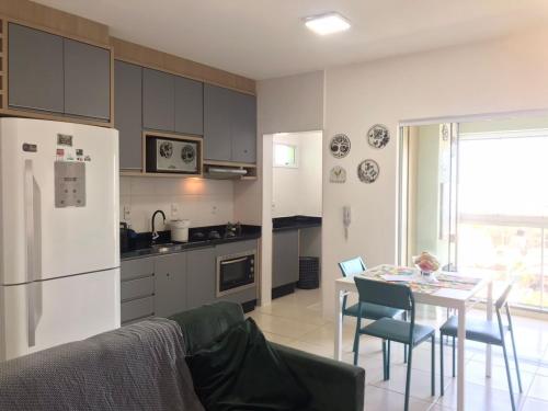 a kitchen with a table and a white refrigerator at Apt- Suíte - Quadra mar - Aeroporto/Beto Carreiro in Navegantes