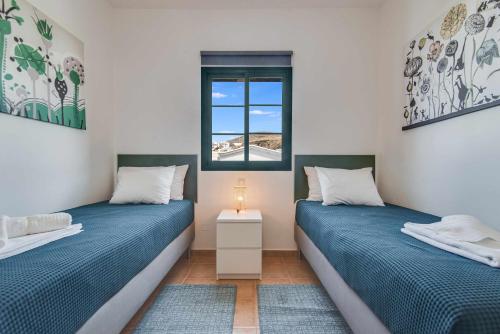 2 Einzelbetten in einem Zimmer mit Fenster in der Unterkunft Residencial Las Candelarias 36 in Agaete