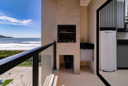 een balkon met een koelkast en uitzicht op de oceaan bij HY Apart Hotel in Bombinhas