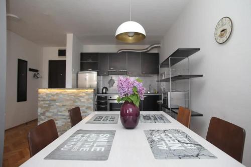 a kitchen with a table with a vase of flowers on it at Heart of the City - 75sqm Suite in Skopje