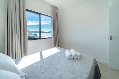 een slaapkamer met een bed en een groot raam bij HY Apart Hotel in Bombinhas
