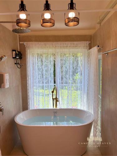 a bath tub in a bathroom with a window at Campson Heaven Resort in Khao Kho