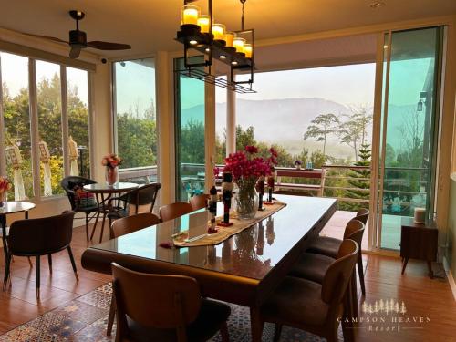 a dining room with a table and chairs and windows at Campson Heaven Resort in Khao Kho