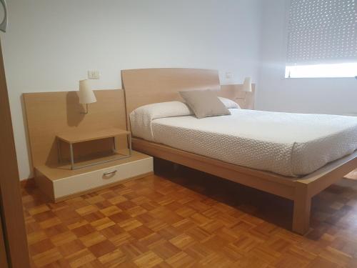 um quarto com uma cama e piso em madeira em Chocolate Alojamiento em Muxía