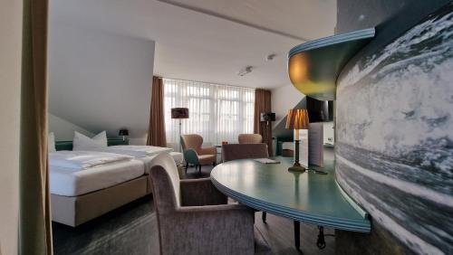 ノルダーナイにあるVilla Neyのベッド、デスク、テーブルが備わるホテルルームです。