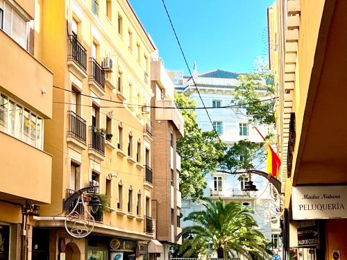 ulica miejska z wysokimi budynkami i palmami w obiekcie PUERTO DELUXE w Maladze