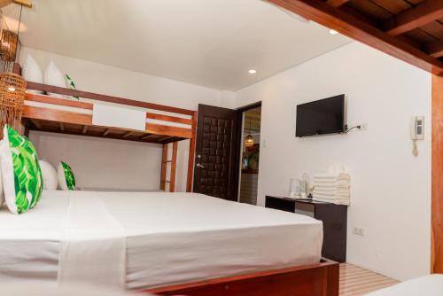 1 dormitorio con 1 cama blanca grande y TV en DENGI INN EL NIDO, en El Nido