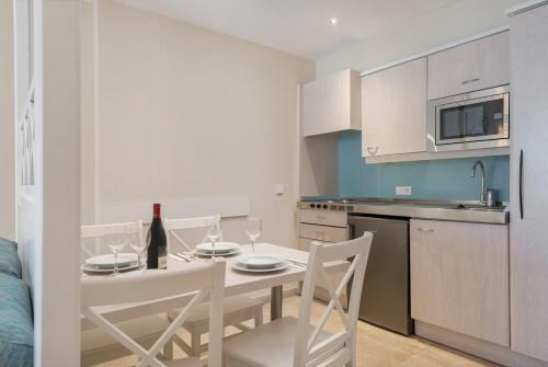 a kitchen with a table with chairs and a bottle of wine at Can Picafort Palace in Can Picafort