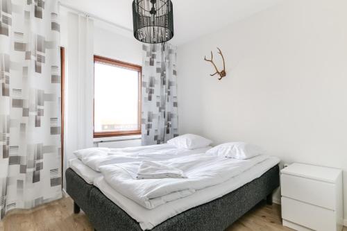 a white bedroom with a bed with a window at Santa's Holiday Homes in Rovaniemi