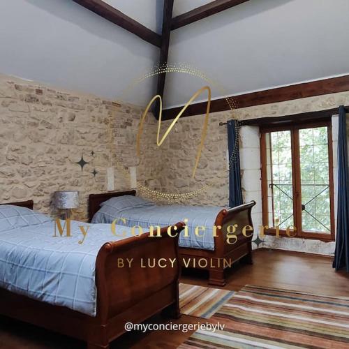 une chambre avec deux lits et un mur en pierre dans l'établissement Le Moulin du Fontcourt, à Chasseneuil-sur-Bonnieure