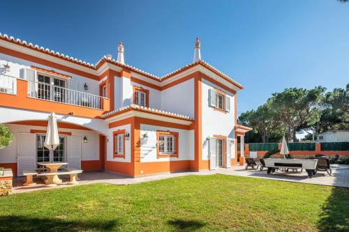 an orange and white house with a yard at Private Villa Ribeiro I Heated Pool, 4 Bed, BBQ, AC, WIFI, BEACH in Albufeira
