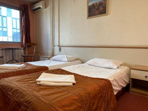 two beds in a hotel room with towels on them at Hotel Brod - Free Parking in Sofia