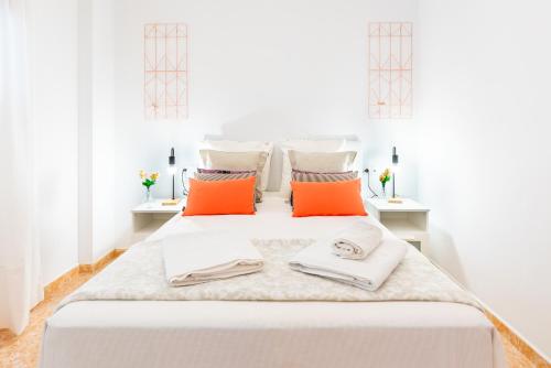 a white bedroom with orange and white pillows on a bed at WintowinRentals Great Apartment, Amazing Location in Parque Mediterráneo in Málaga