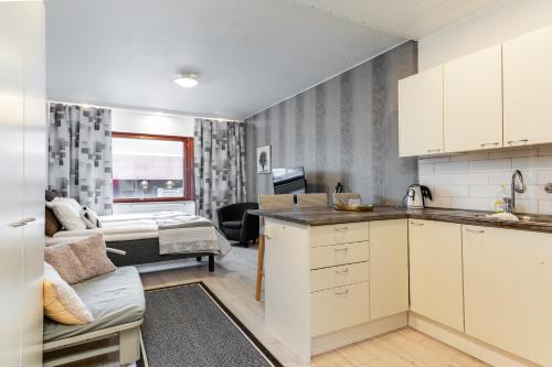 a kitchen with white cabinets and a living room at Santa's Holiday Homes in Rovaniemi