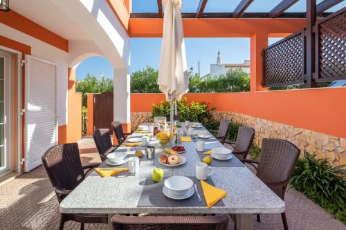 a table and chairs on a patio with an umbrella at 4 Bed Private Villa Ribeiro II with heated pool, garden, wi-fi in Albufeira
