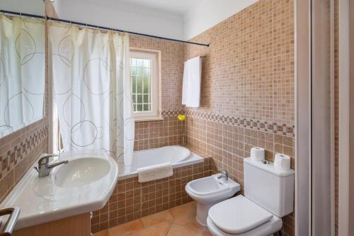 a bathroom with a sink and a toilet and a tub at 4 Bed Private Villa Ribeiro II with heated pool, garden, wi-fi in Albufeira