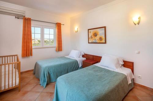 a room with two beds and a window and a crib at 4 Bed Private Villa Ribeiro II with heated pool, garden, wi-fi in Albufeira