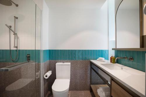 a bathroom with a toilet and a sink and a shower at Holiday Inn & Suites Geelong by IHG in Geelong