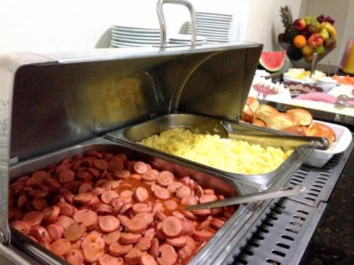 a buffet of food with sausage and other food at Umbu Hotel Porto Alegre - Centro Histórico - Prox Aeroporto in Porto Alegre