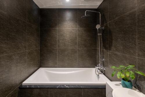 a bath tub in a bathroom with brown tiles at Taiyo Hotel & Apartment in Da Nang